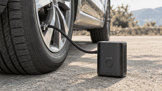 Portable tire inflator beside a car wheel